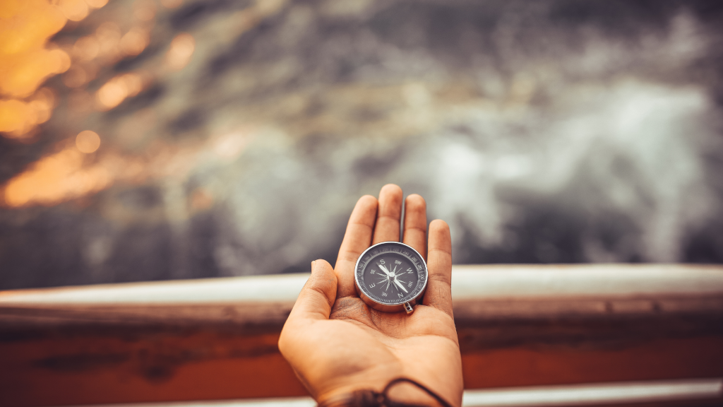 Avu&ccedil; i&ccedil;inde tutulan k&uuml;&ccedil;&uuml;k bir pusula. Muhtemelen bir adam elinde duruyor ve adam y&ouml;n bulmaya &ccedil;alışıyor.