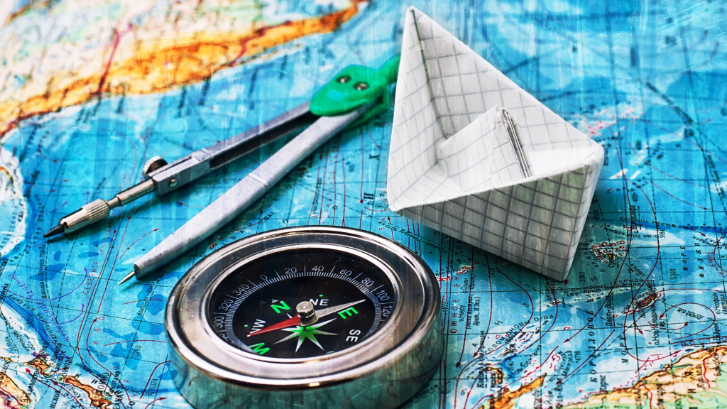 Kağıttan bir gemi yanında duran pusula.